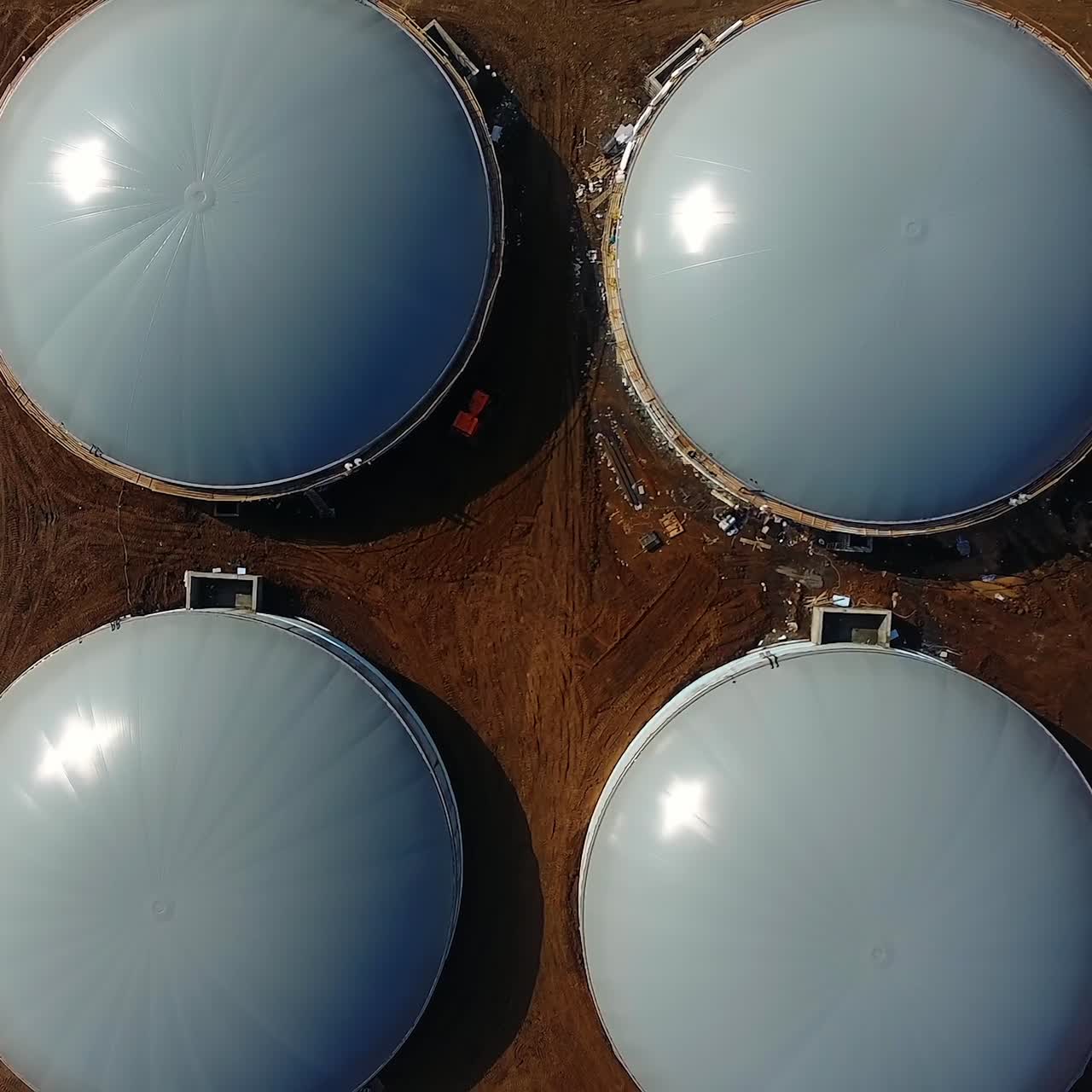 Large storage tanks on biogas plant. Modern equipment for biogas production on field. Innovative reservoirs for renewable energy. Top view. Camera rising.