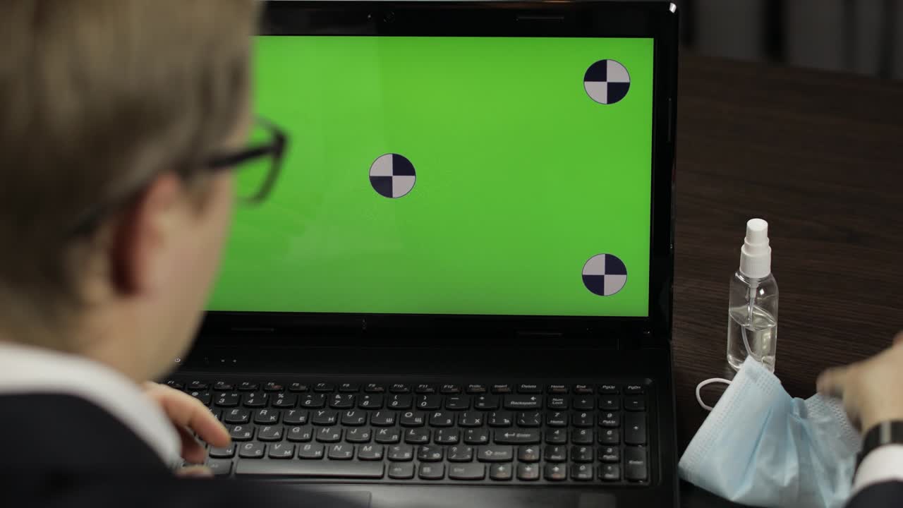 Man removes medical mask, takes sanitizer and use near laptop with green screen