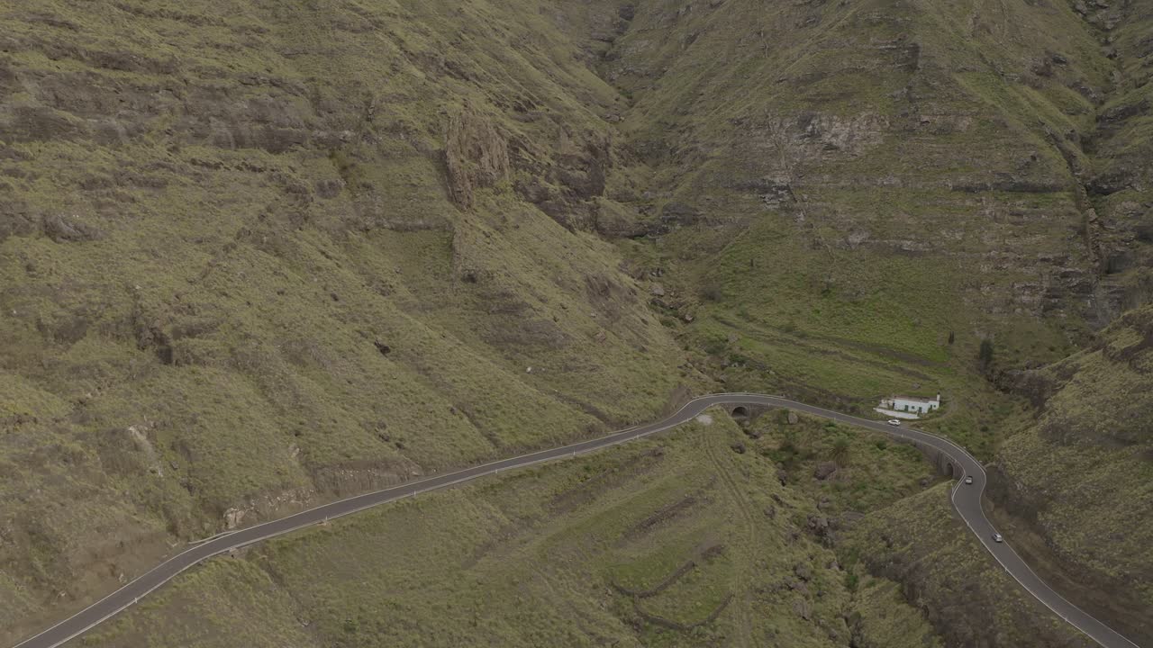 toma panorámica de un camión conduciendo a través de una carretera con curvas en un cañón con montañas