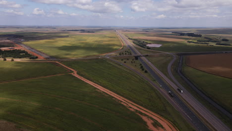 drone shot of motorway surrounded by lush green agricultural farming fields