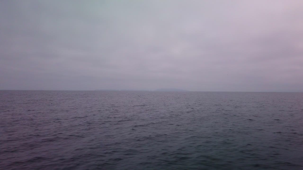 Gimbal shot from a moving boat of the open ocean with the Channel Islands barely visible in the marine layer and fog off the coast of Ventura, California