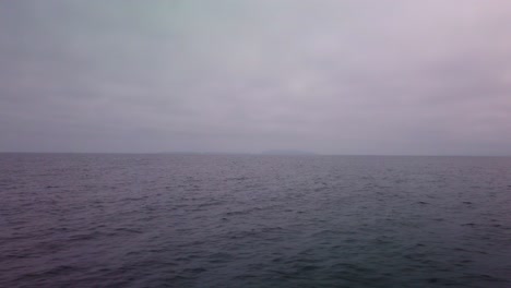 Gimbal-shot-from-a-moving-boat-of-the-open-ocean-with-the-Channel-Islands-barely-visible-in-the-marine-layer-and-fog-off-the-coast-of-Ventura,-California