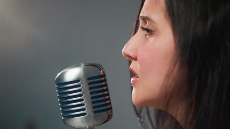 intense close-up of a female singer passionately singing into a vintage microphone, with a blurred background emphasizing focus