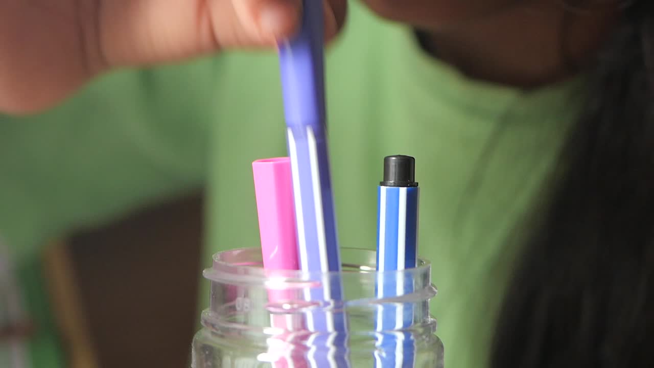 Child Organizing Pens in a Jar