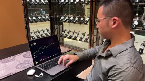 rich asian millennial man checking stock brokerage portfolio gains inside luxurious home