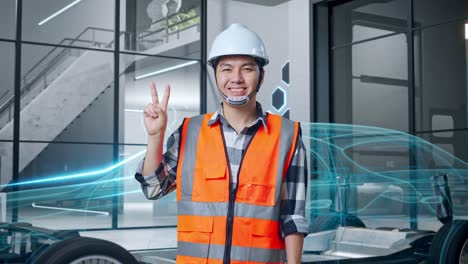 ingeniero sonriente en una fábrica moderna que muestra el signo v