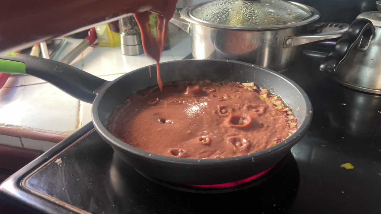Honduras refried beans cooking in a pan, showing traditional frijoles prepared at home, a common local dish made on the stove using simple ingredients and everyday cooking methods.