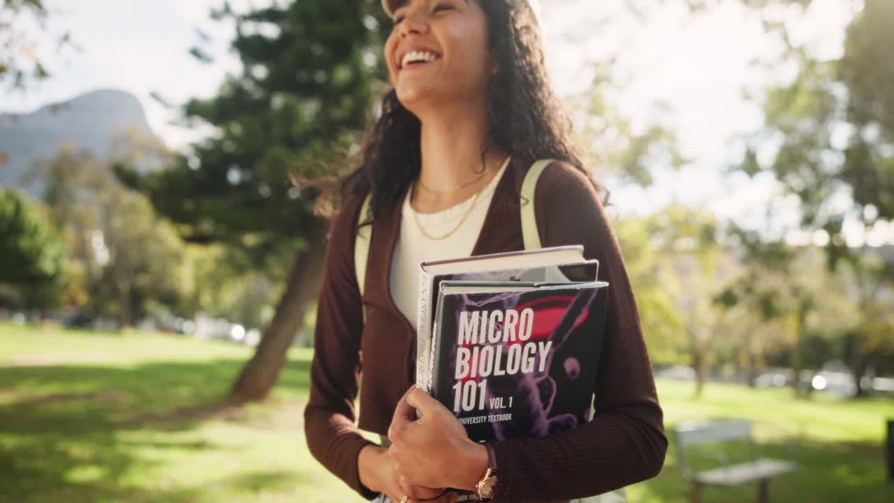 A smiling student on campus with a biology textbook