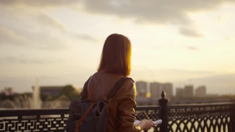 vista posteriore di una ragazza carina allo zenzero che disegna e cammina in città al tramonto