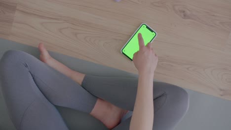 초록색 화면으로 된 전화는 바닥에 누워 있고 여성들은 스와이프를 합니다.