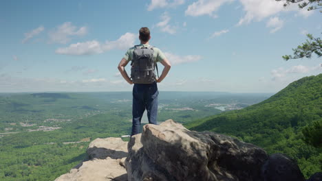 man climbing to mountain summit or peak and standing proudly looking at the amazing view seen from above