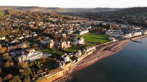 Luftaufnahme-Der-Stadt-Sidmouth-Neben-Der-Küste,-Die-In-Sonnenaufgangslicht-Getaucht-Ist