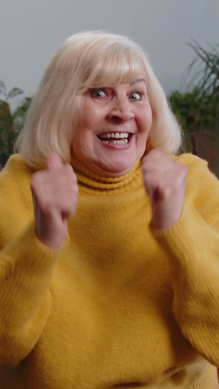 Nonna entusiasta, sorpresa e scioccata da inaspettate notizie di vittoria, che celebra con una reazione di stupore.