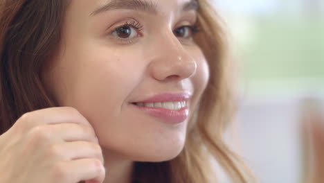 Mujer-Feliz-Mirando-La-Cara-En-El-Espejo-En-El-Baño-De-Casa.-Retrato-Mujer-Sonriente