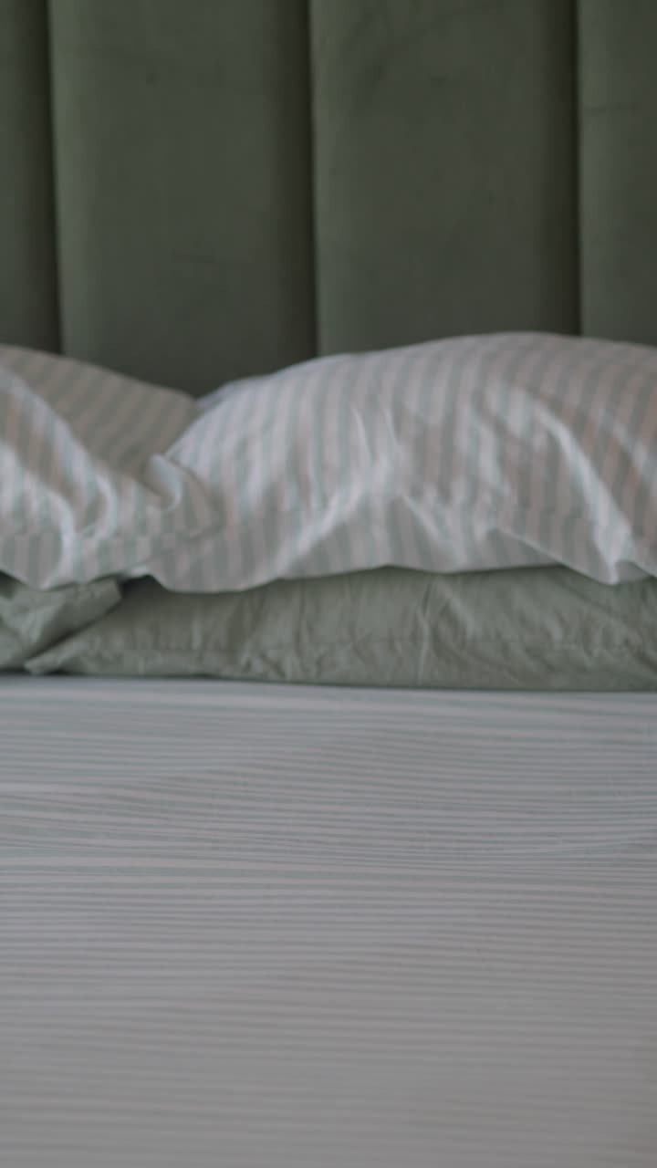 Tangan Menata dan Merapikan Bantal Bergaris di Atas Tempat Tidur