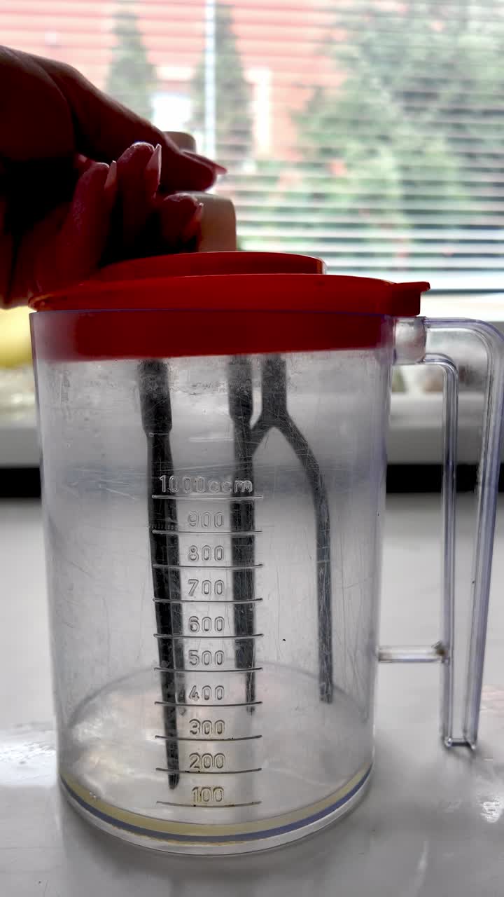 Batir huevo con batidora de cocina retro manual en jarra medidora