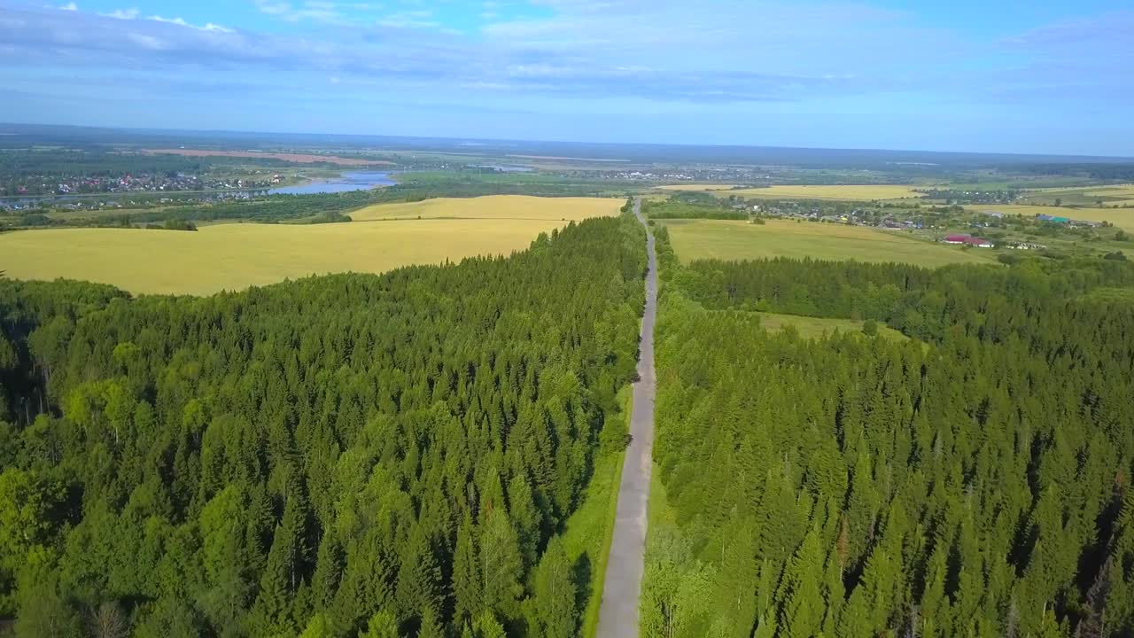 숲 과 농경지 를 가로지르는 시골 도로 의 공중 사진
