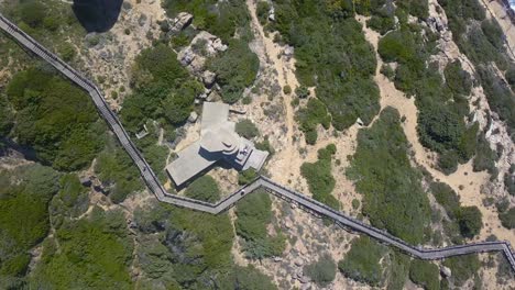 Toma-Aérea-Cenital-De-Una-Pasarela-Que-Baja-En-Un-Cabo-Del-Sur-De-España,-Cádiz.