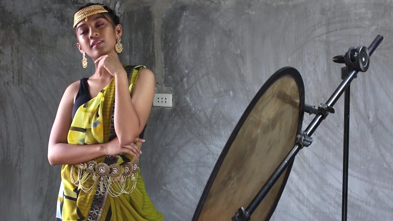 pretty asian young model dress up like an indian posing for a photoshoot inside a bare studio with just the natural light and reflector.