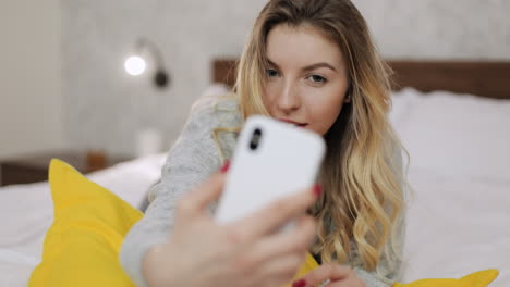 woman taking a selfie on her phone in bed