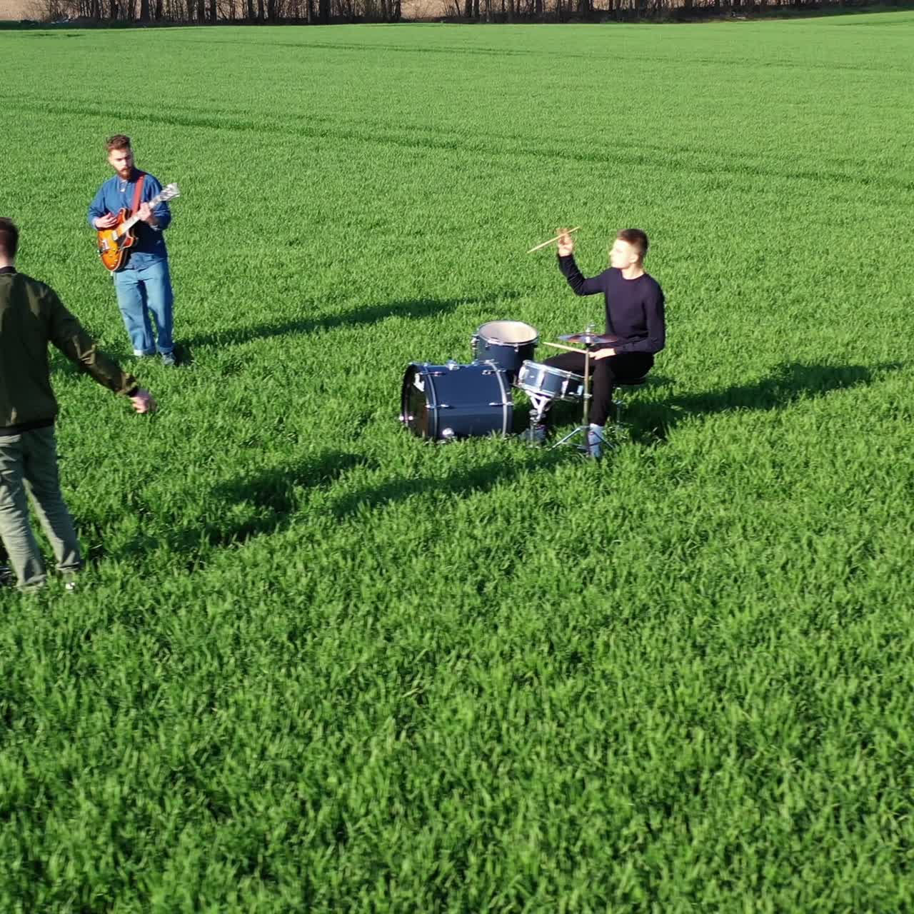 Young men of a music band playing musical instruments. Group of musicians performing music and singing on green field background. Top view