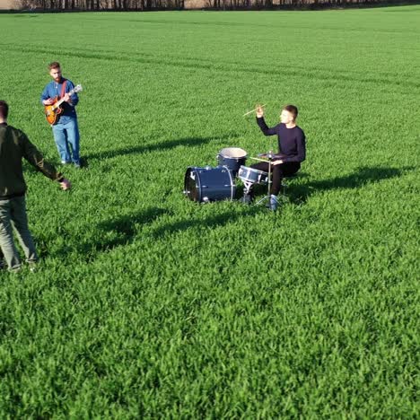 young men of a music band playing musical instruments. group of musicians performing music and singing on green field background. top view