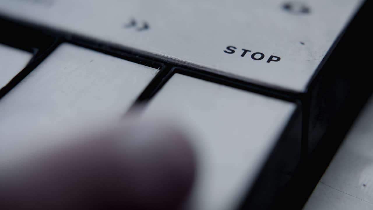Finger Pressing Stop Button on Vintage Electronic Device