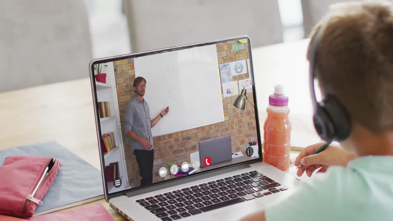 escolar caucásico teniendo clase en la llamada de video portátil con el maestro masculino en cámara lenta
