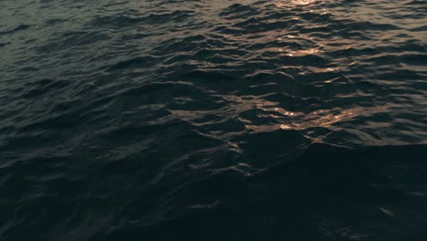 toma en cámara lenta del sol dorado que se refleja durante la puesta de sol en las olas del océano azul