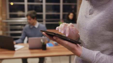 mid section of creative businesswoman using digital table in modern office