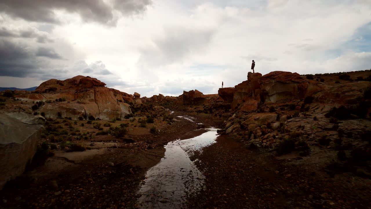 Tourists standing on rocky outcrops exploring Siloli desert river valley