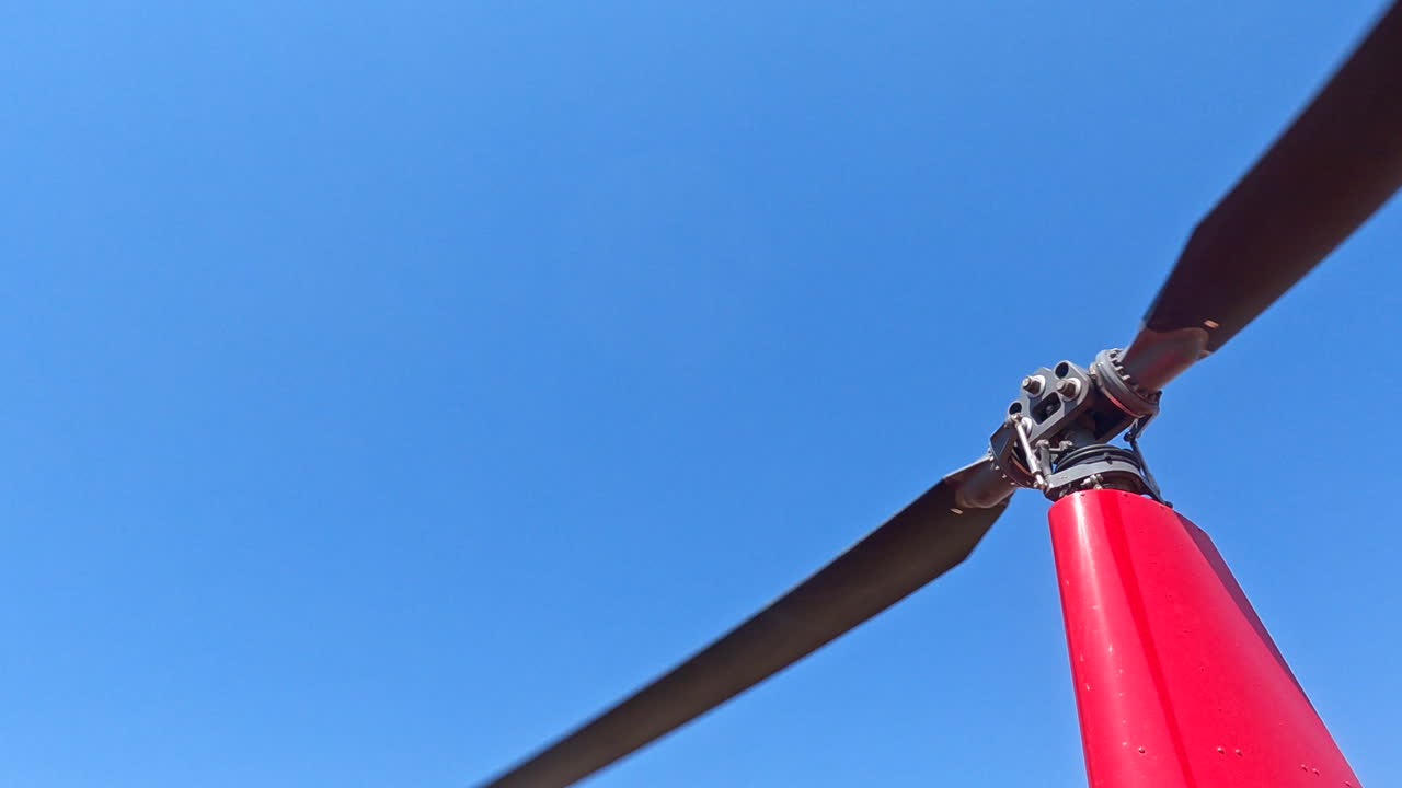 빨간색 헬리터의 회전하는 메인 로터 블레이드의 근접 사진