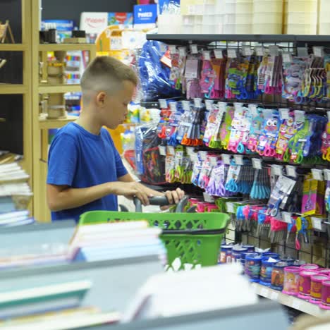 vinnitsa, ukraine - august 20, 2018: beautiful boy choosing school stationery at a supermarket. shopping for school