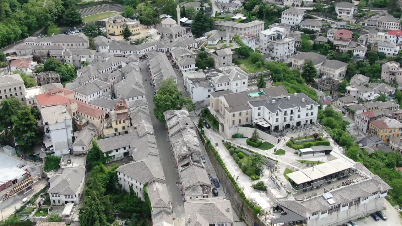알바니아의 드론 뷰가 중세 도시 위의 게이로카스터에서 날아다니며 벽돌 갈색 지붕 집을 보여줍니다.