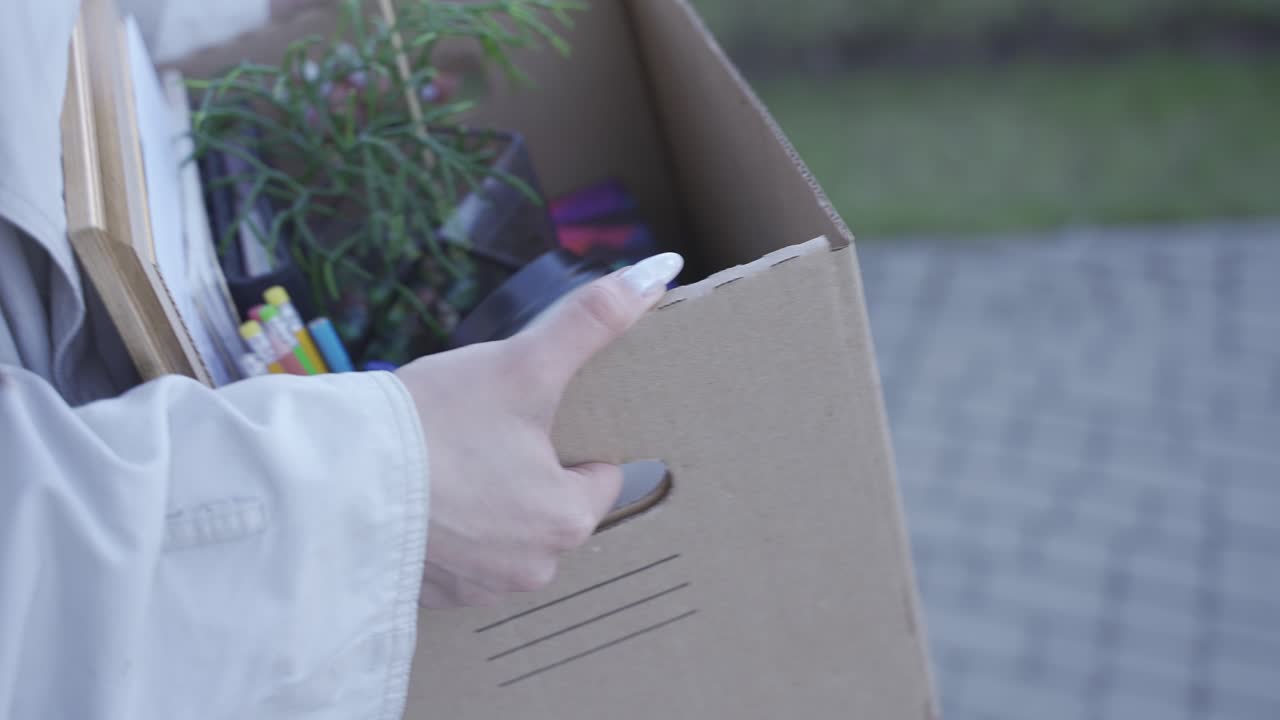 Close-up of woman's hands carrying things in a box. The girl has been fired.