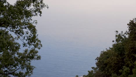 The-camera-tilts-up-from-the-forest-of-the-Italian-coastline-to-the-sea-and-the-clouds-above