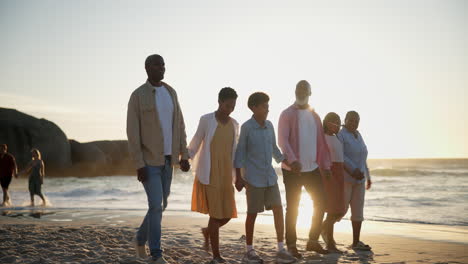 family, children and grandparents walk on beach