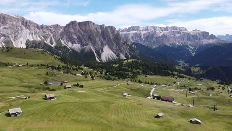 valle de seceda y val gardena en tirol del sur, alpes italianos, dolomitas, italia - vista aérea de drones del valle verde, cabañas y altas montañas