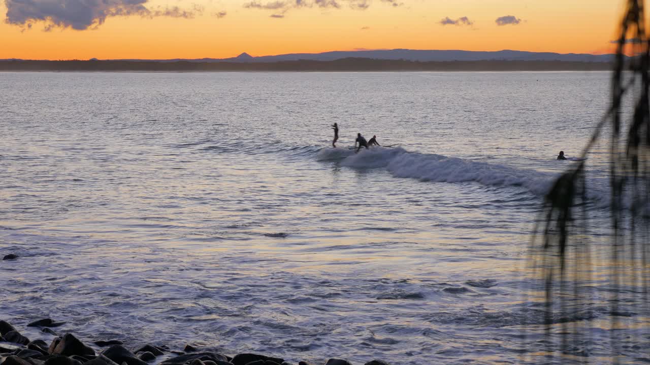 gente surfeando durante la hora dorada en el parque nacional de noosa en queensland, australia