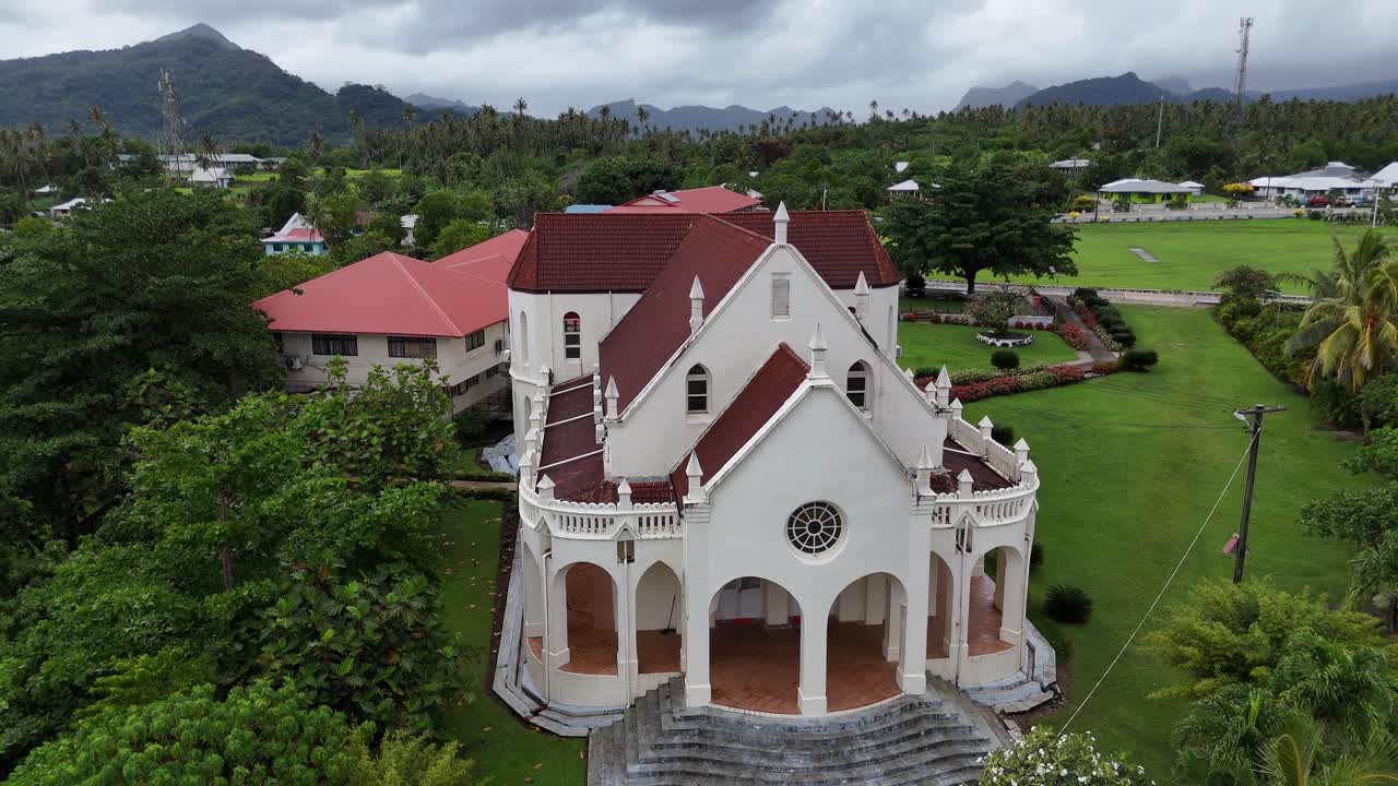 Impresionante vista aérea con dron de una iglesia blanca tradicional rodeada de la vibrante y exuberante vegetación y los paisajes tropicales de Samoa en el Pacífico Sur