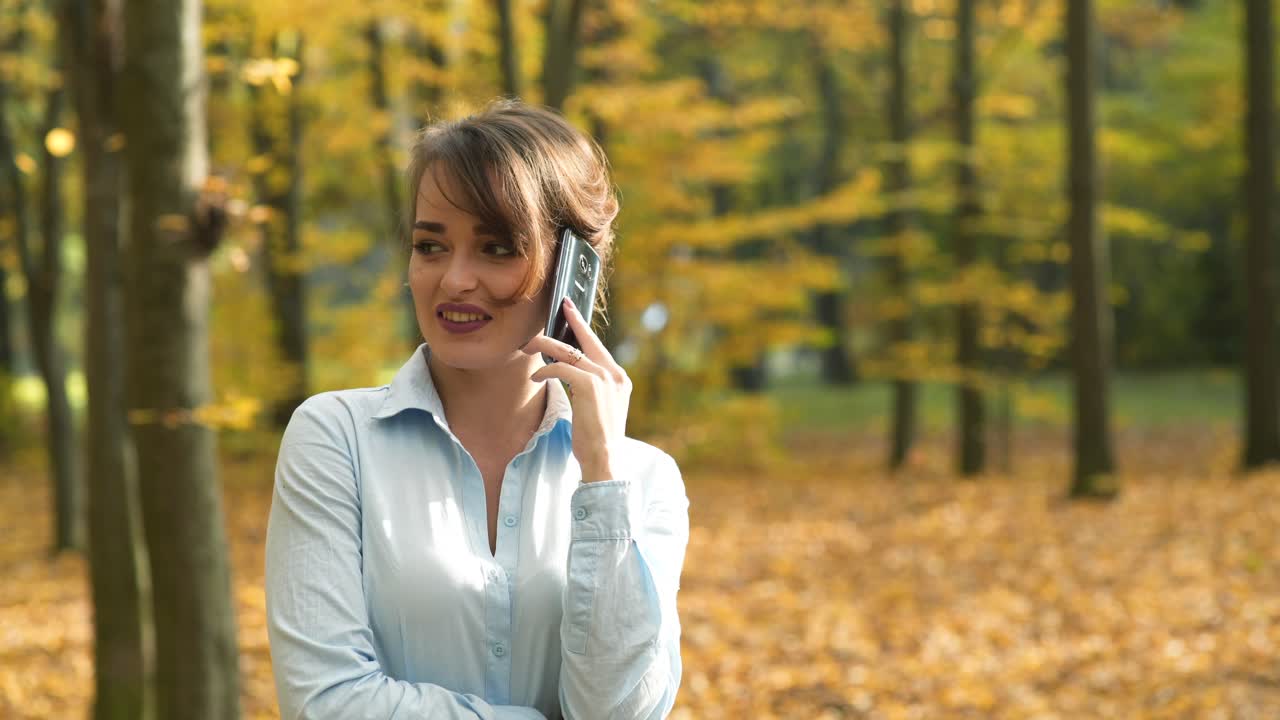 Woman talking on phone. Attractive woman talking on phone in autumn park