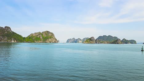 majestic limestone karsts rise dramatically from the tranquil turquoise waters of ha long bay, creating a mesmerizing seascape where emerald-topped islands stretch endlessly toward the misty horizon