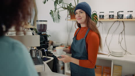 a barista serves a coffee to a customer in a cafe