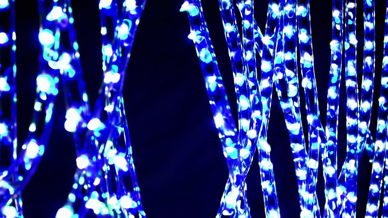 Close-up video of glowing blue LED lights on twisted wires, shot from a side angle