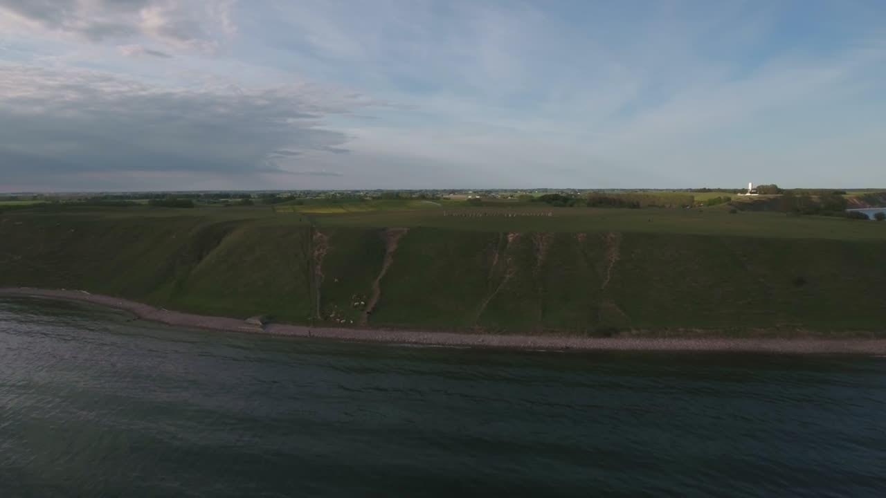 colina empinada con vacas por ales stenar en la noche con un cielo dramático en el sur de suecia skåne österlen kåseberga, avance aéreo tiro ancho extremo lento