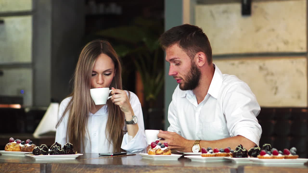 Young man pointing on girl's telephone while making booking online and discussing ,male and female colleagues communicating on coffee break checking updated on education web page via smartphone
