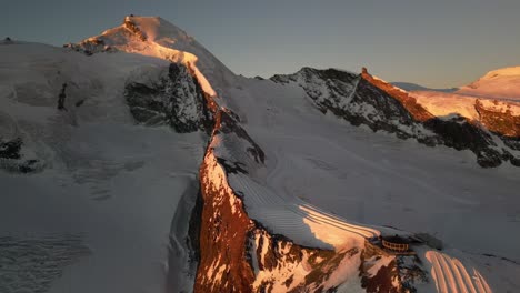 aerial view of a snowy and rocky mountain ridge during a sunrise in the swiss alps