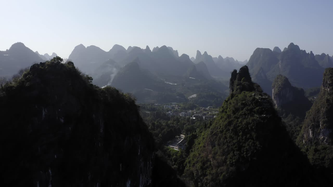 amplia toma aérea de un pueblo aislado rodeado de montañas en yangshuo, china