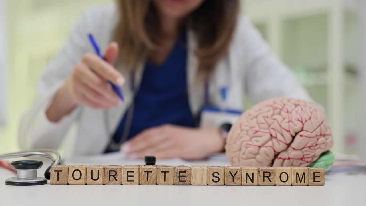 Blocos de madeira formam as palavras síndrome de Tourette perto de um modelo de cérebro.