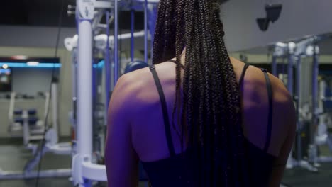 de una chica atlética disparada mientras usa una máquina de cable para hacer ejercicio en un gimnasio vacío